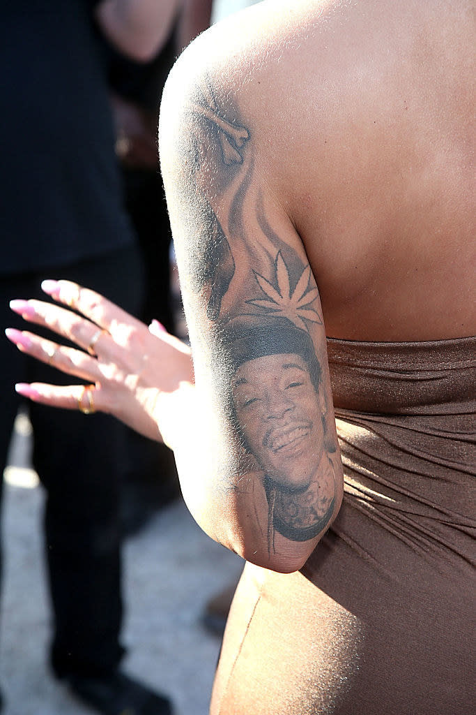 A portrait of a smiling Wiz Khalifa on the back of Amber Rose's arm
