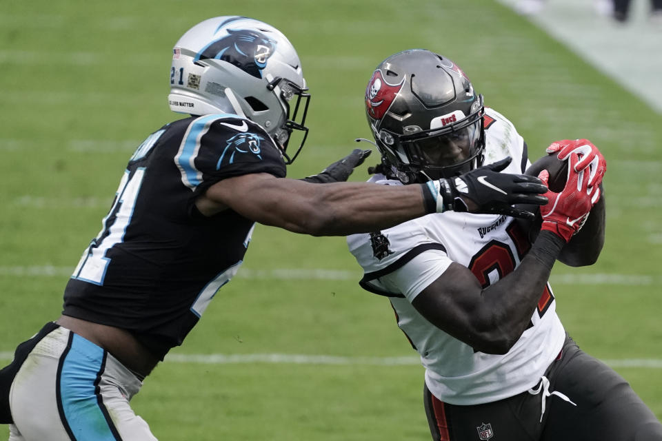 Tampa Bay Buccaneers running back Ronald Jones (27) runs agaqinst Carolina Panthers outside linebacker Jeremy Chinn (21) during the second half of an NFL football game, Sunday, Nov. 15, 2020, in Charlotte , N.C. (AP Photo/Gerry Broome)