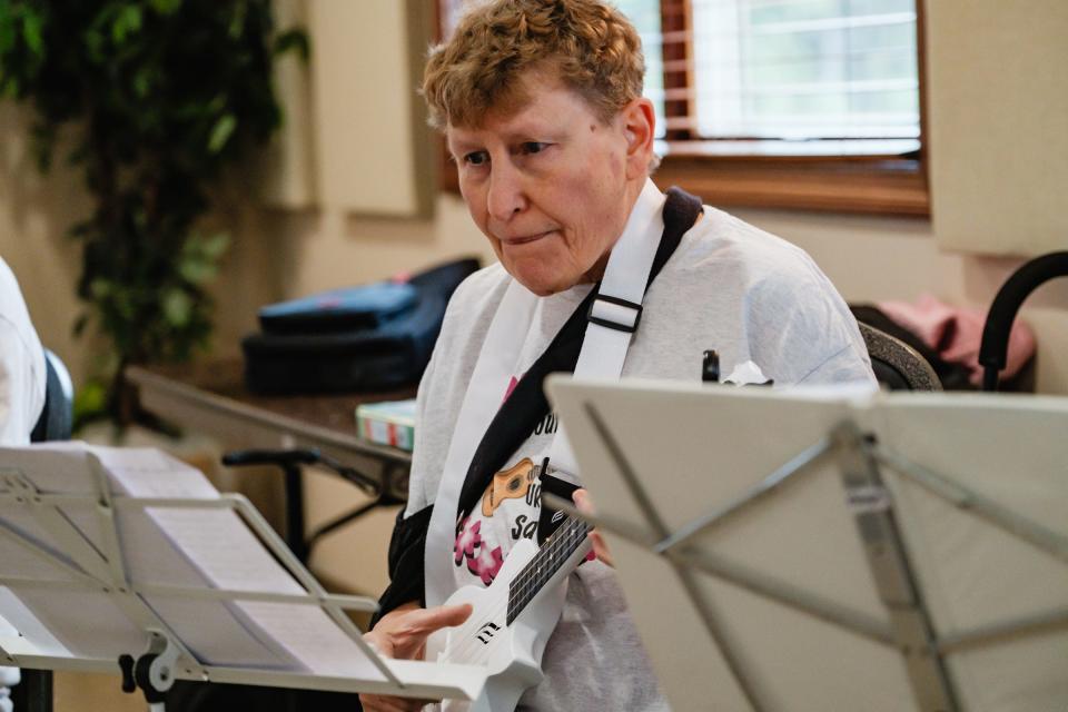 Despite recovering from recent rotator cuff surgery, Sue Kloc, from New Philadelphia, plays during a special performance by the T-County Ukulele Squad, at the Tuscarawas County Senior Center in Dover.