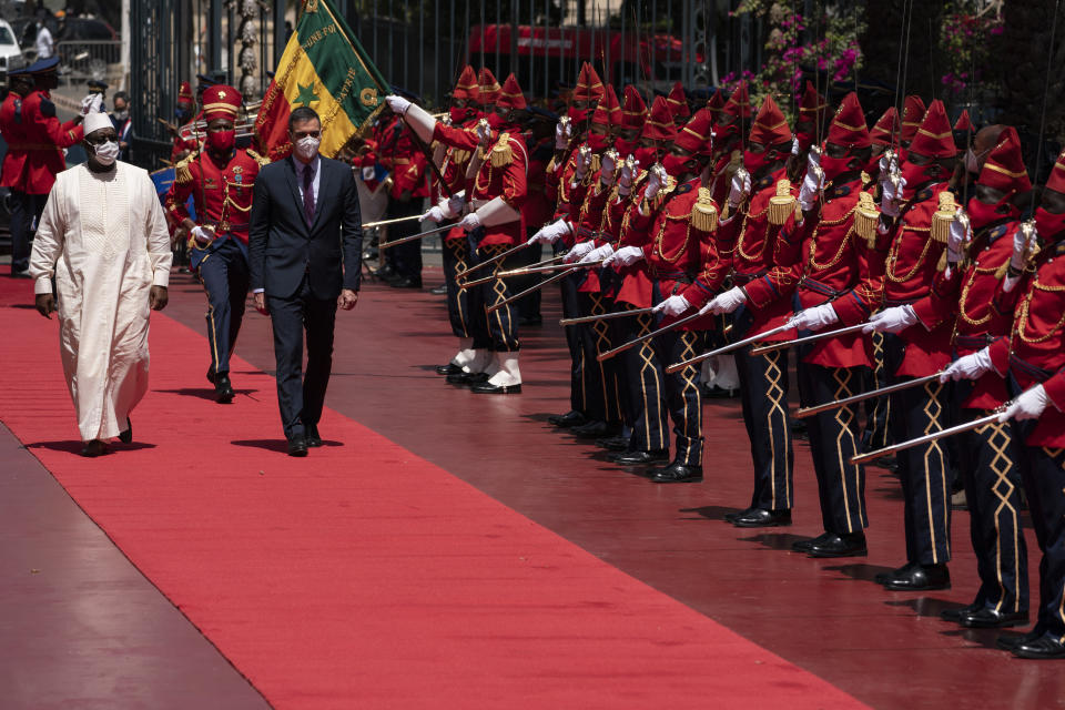 Senegal's President Macky Sall, left, and Spanish Prime Minister Pedro Sanchez review the troop during a welcoming ceremony at the presidential palace in Dakar, Senegal, Friday, April 9, 2021. Sanchez is on a mini-tour to Angola and Senegal that are key in the European country's new push to bolster ties with the neighboring continent and mitigate the migration flows that many fear could increase as a consequence of the coronavirus pandemic. (AP Photo/Leo Correa)