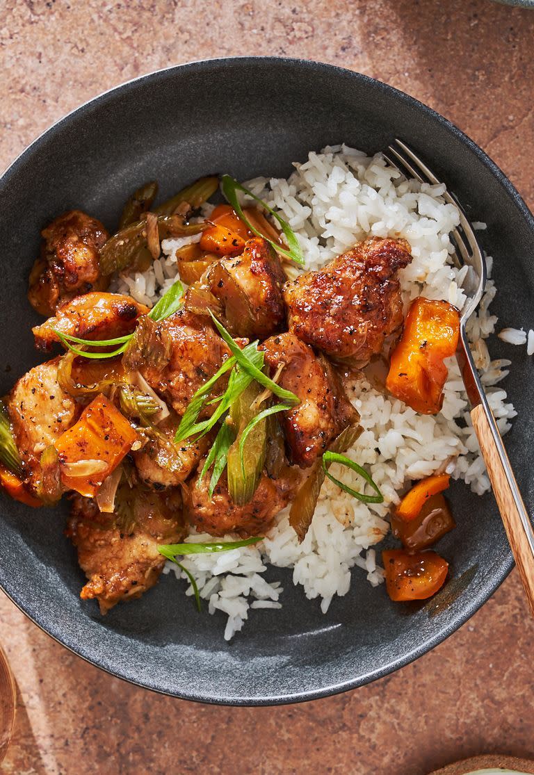 black pepper chicken topped with scallions over white rice in a black bowl