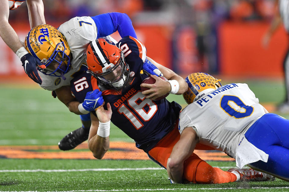 Syracuse quarterback Garrett Shrader, center, is tackled by Pittsburgh linebacker SirVocea Dennis (7) and linebacker John Petrishen (0) during the first half of an NCAA college football game in Syracuse, N.Y., Saturday, Nov. 27, 2021. (AP Photo/Adrian Kraus)