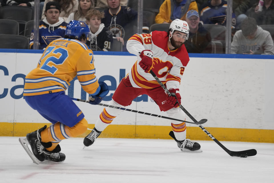 Calgary Flames' Dillon Dube (29) passes around St. Louis Blues' Justin Faulk (72) during the first period of an NHL hockey game Tuesday, Jan. 10, 2023, in St. Louis. (AP Photo/Jeff Roberson)