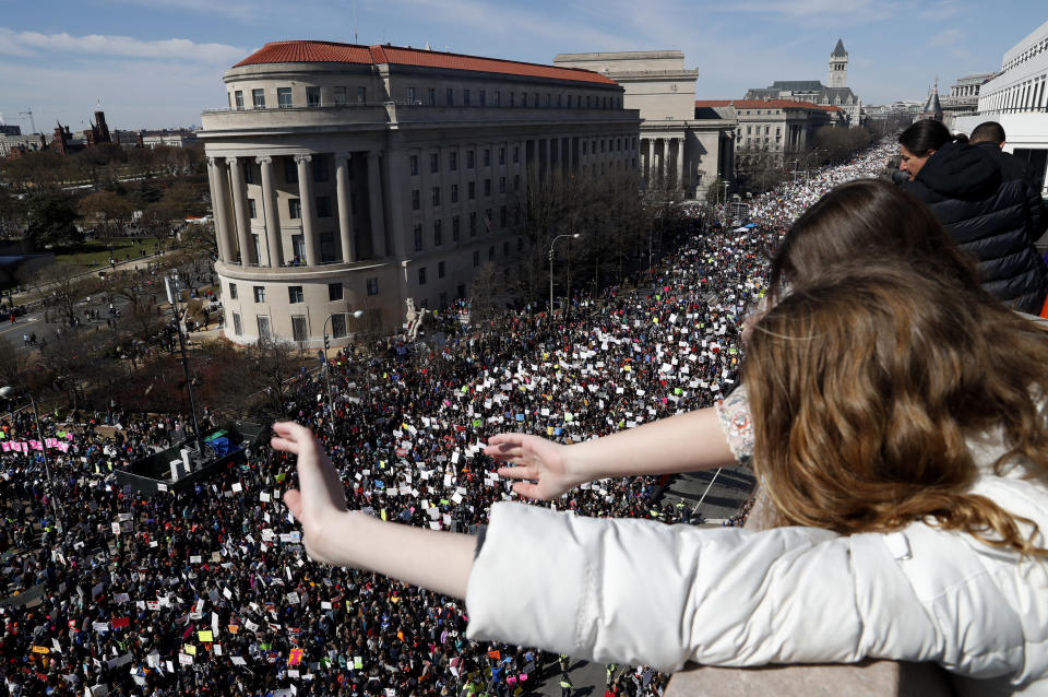 Young girls wave down at marchers from the balcony of the Newseum.&nbsp;