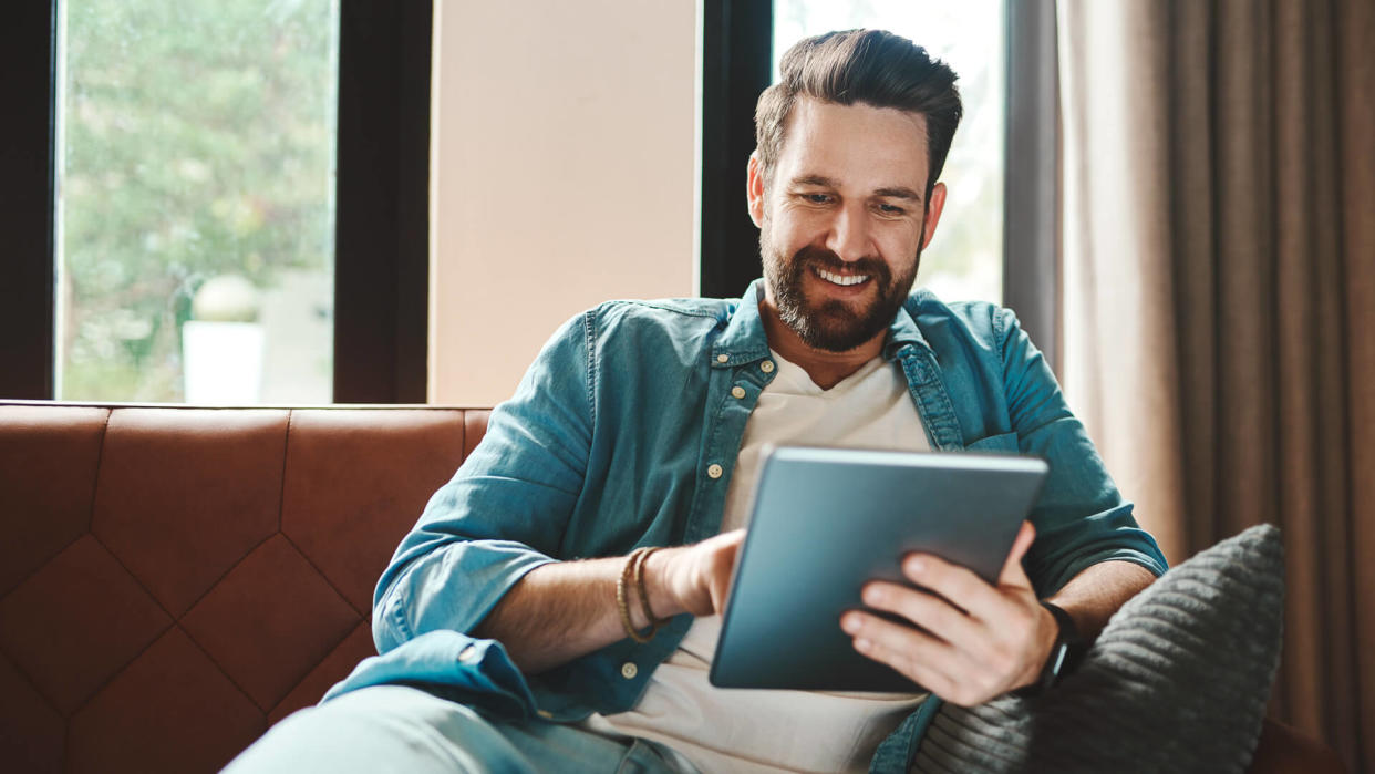 Cropped shot of a handsome young man using a tablet while chilling on the sofa at home.