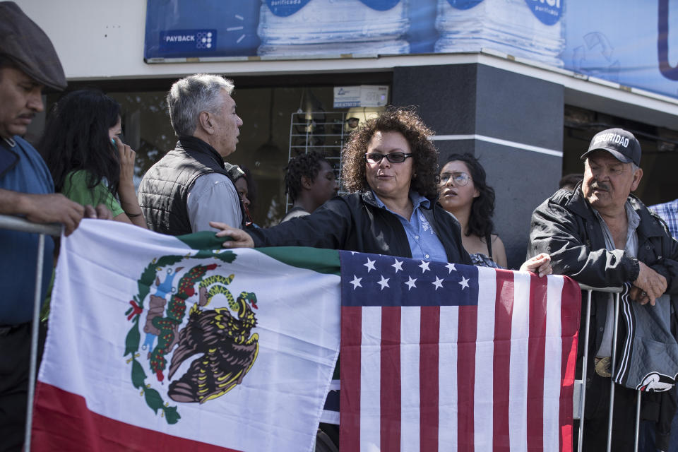 Lilia Lara, una residente de Tijuana, coloca las banderas de México y Estados Unidos sobre una valla en una plaza donde el presidente Andrés Manuel López Obrador planea realizar un mitin en Tijuana, México, el sábado 8 de junio de 2019. (AP Foto/ Hans-Maximo Musielik)