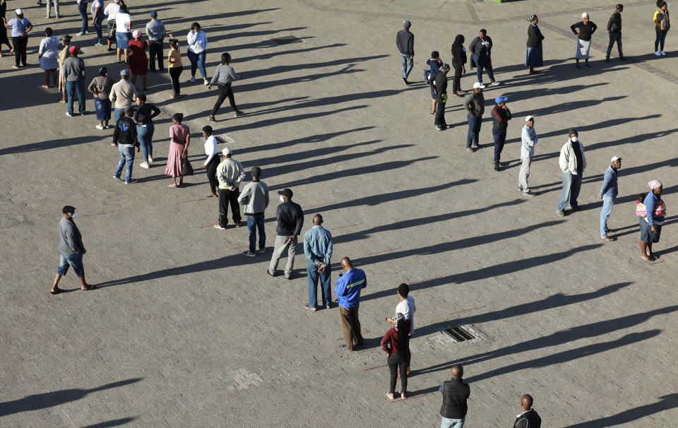 In this photo taken Thursday, April 2, 2020 people practice social distancing outside a testing clinic in Khayelitsha, Cape Town, South Africa. South Africa, one of the world's most unequal countries with a large population vulnerable to the new coronavirus, may have an advantage in the coronavirus outbreak, honed during years battling HIV and tuberculosis: the know-how and infrastructure to conduct mass testing. (AP Photo/Nardus Engelbrecht)