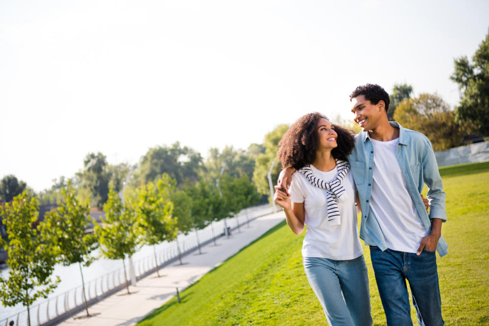 Couple walking arm in arm, smiling, in a sunny park setting