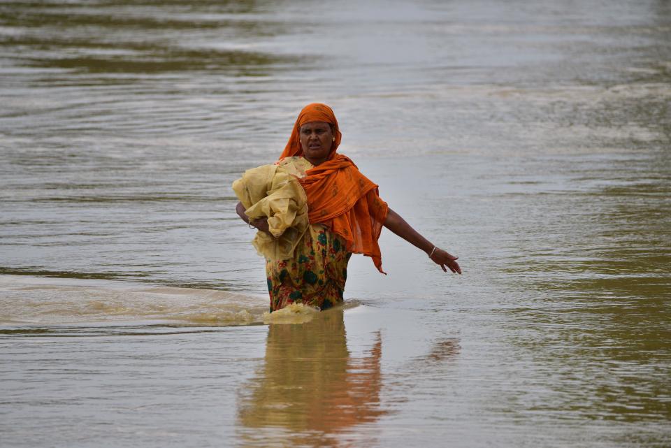 A woman wades through flood water after heavy downpours in the Kampur area in Nagaon district of India's northeast state of Assam, May 17, 2022. / Credit: Str/Xinhua/Getty