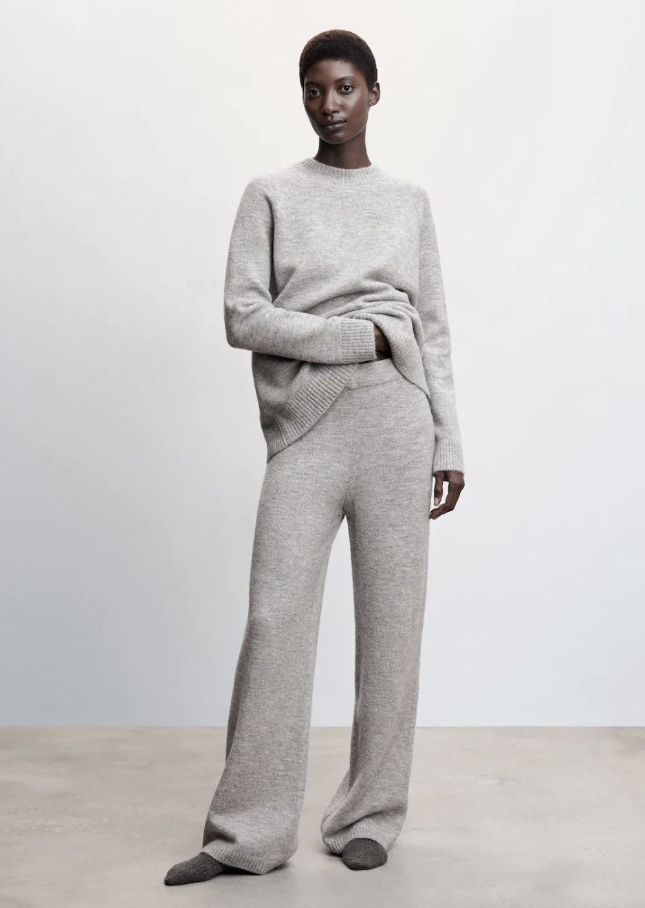 model wearing grey sweater and Knit Trousers in light heather grey (photo via Mango)