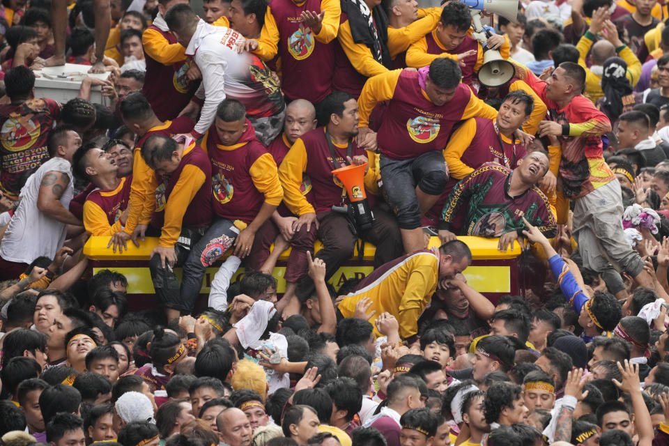 Devotees react as they try to block others from climbing on the glass-covered cart carrying Black Nazarene during its annual procession which was resumed after a three-year suspension due to the coronavirus pandemic on Tuesday, Jan. 9, 2024 in Manila, Philippines. A mammoth crowd of mostly barefoot Catholic devotees joined a chaotic procession through downtown Manila Tuesday to venerate a centuries-old black statue of Jesus Christ with many praying for peace in the Middle East where Filipino relatives work. (AP Photo/Aaron Favila)