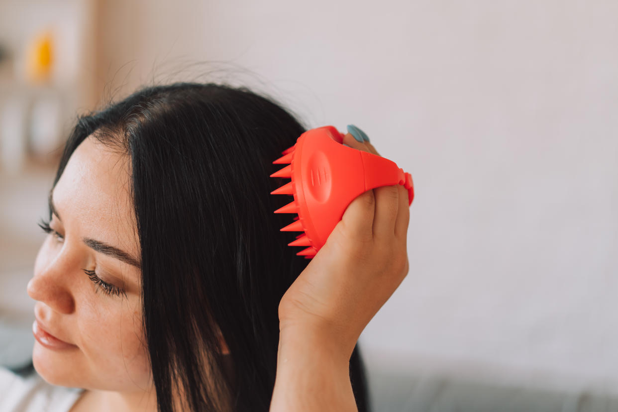 Woman using a scalp massager on her hair