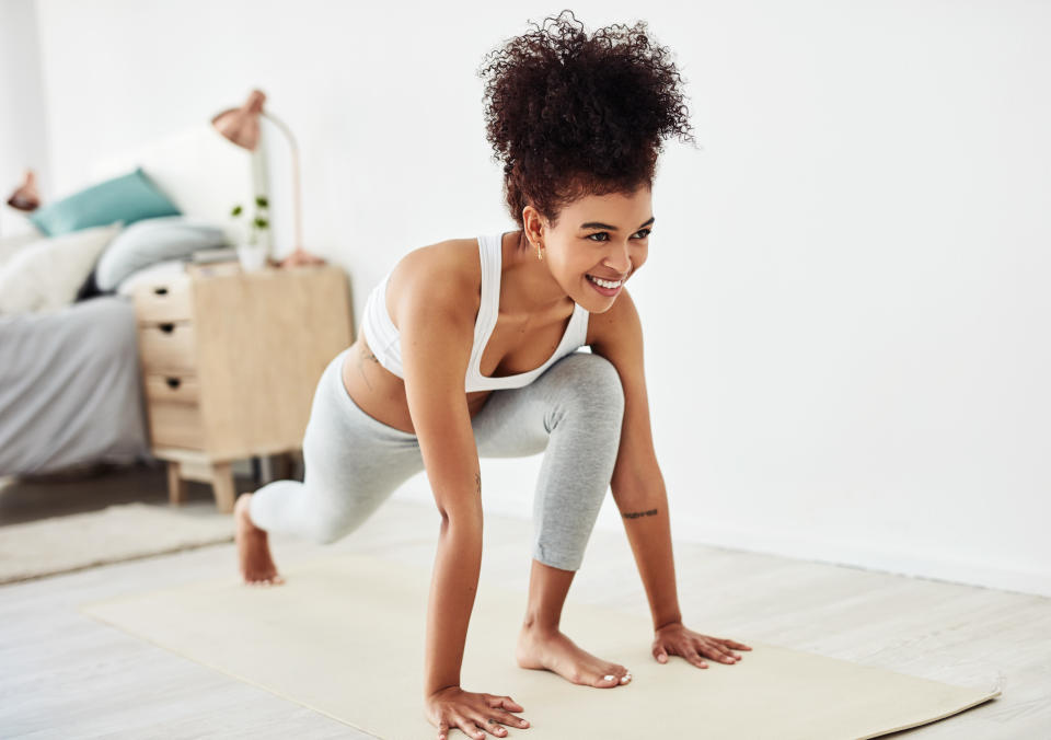 Smiling woman working out at home, doing yoga in her bedroom