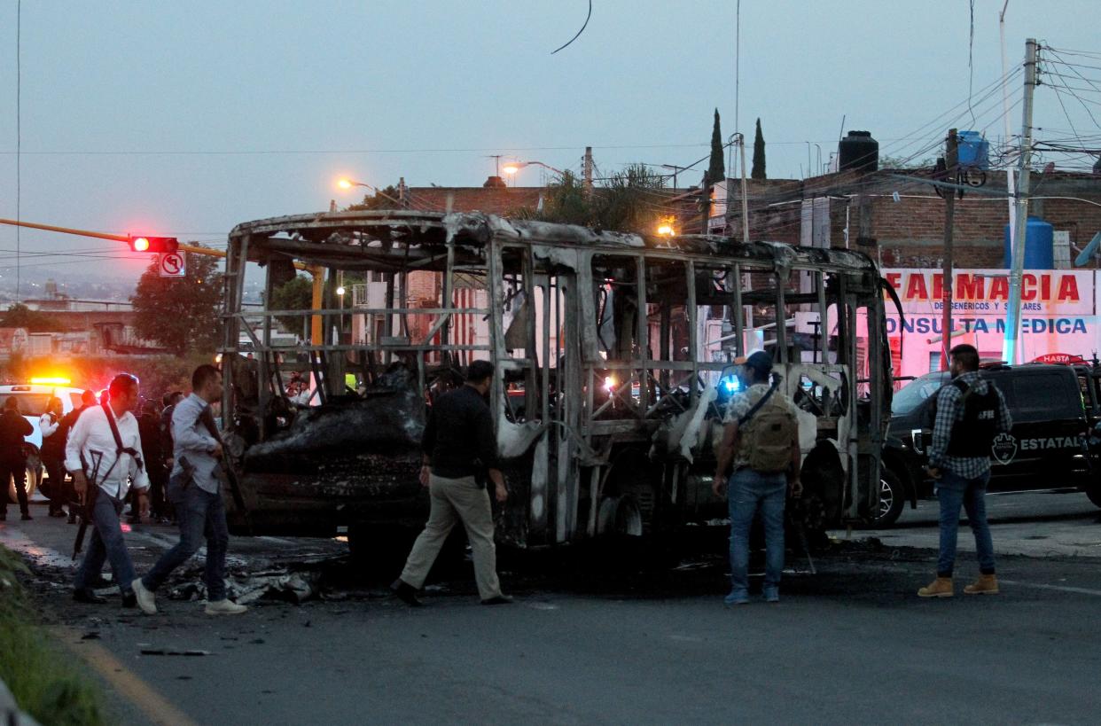 Members of the State Prosecutor's Office and Municipal Police guard the area where gang members set a bus on fire blocking a highway to prevent authorities from chasing them while they were clashing with another gang, in Zapopan, Jalisco State, Mexico, on August 9, 2022. - According to the authorities, no one was injured. (Photo by ULISES RUIZ / AFP) (Photo by ULISES RUIZ/AFP via Getty Images)