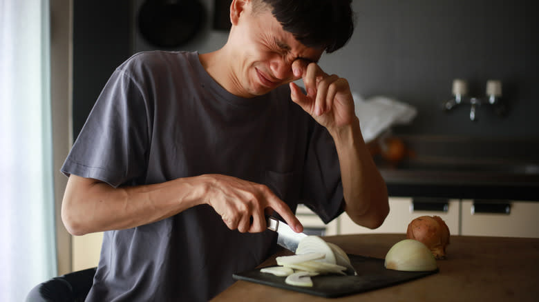 person crying while cutting onions