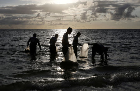 Policemen collect trash in the waters off the beach at the holiday island of Boracay during the first day of a temporary closure for tourists, in Philippines April 26, 2018. REUTERS/Erik De Castro