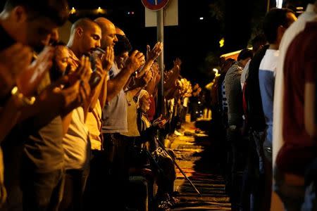 Palestinian men take part in evening prayers inside Jerusalem's Old City, next to the Lion's Gate July 20, 2017. REUTERS/Ammar Awad