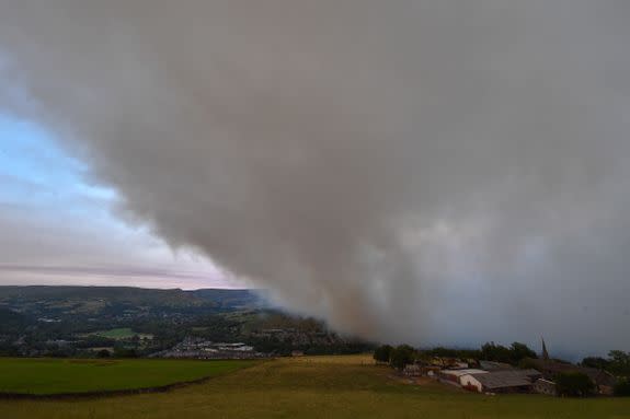 A large cloud of smoke covers the village of Mossley as a large wildfire sweeps across the moors.