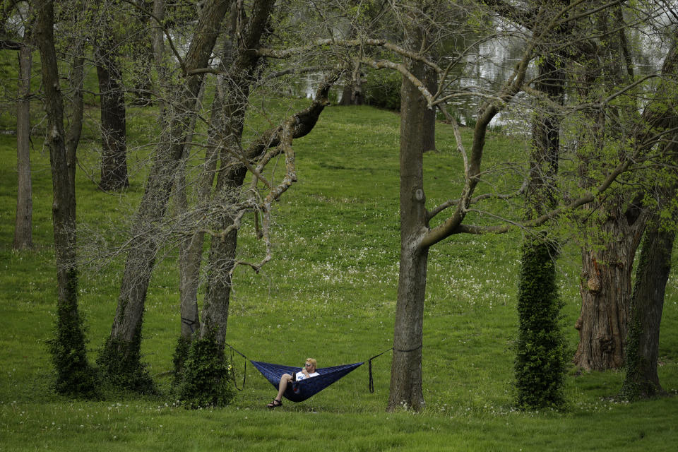 FILE - In this April 26, 2020, file photo, a man sits in a hammock on the University of Kansas campus in Lawrence, Kan. (AP Photo/Charlie Riedel, File)