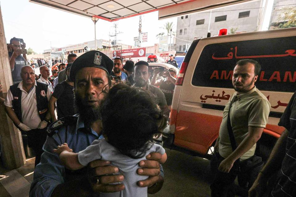 <p>Mustafa Hassona/Anadolu via Getty</p> Residents in Gaza are photographed next to an ambulance following search and rescue operations