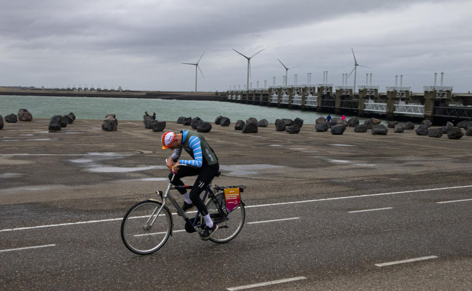 A competitor battles gale force winds during the Dutch Headwind Cycling Championships on the storm barrier Oosterscheldekering, rear, near Neeltje Jans, south-western Netherlands, Sunday, Feb. 9, 2020. (AP Photo/Peter Dejong)