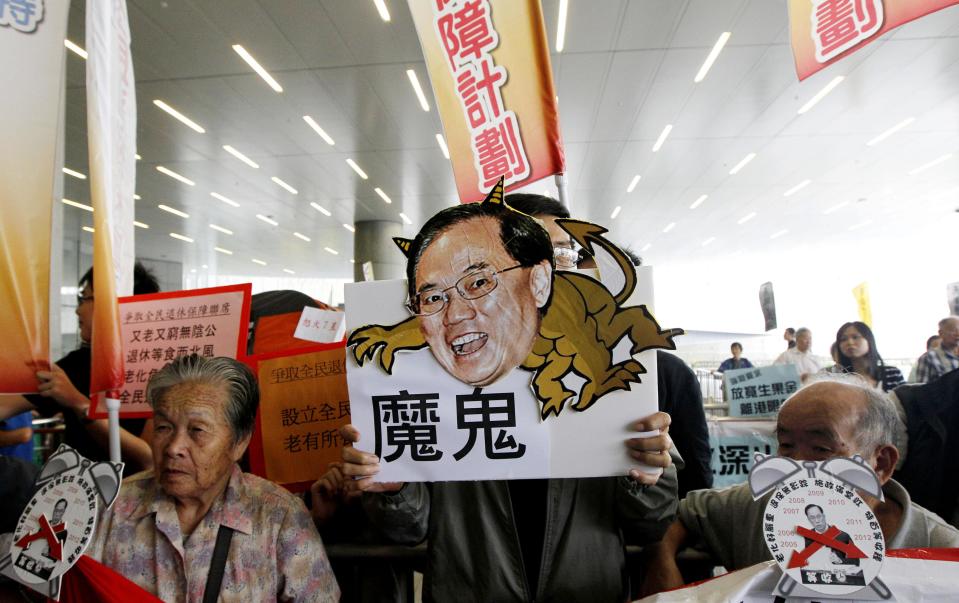 Elderly protesters hold a picture of Hong Kong Chief Executive Donald Tsang with the word "Devil", demanding better welfare from Hong Kong government outside the new Legislative Council building in Hong Kong Wednesday, Oct. 12, 2011. Hong Kong will resume a program to sell thousands of affordable apartments a year, the city's leader said Wednesday as he unveiled a key measure in his annual policy speech aimed at cooling public anger over the city's widening rich-poor gap. (AP Photo/Kin Cheung)