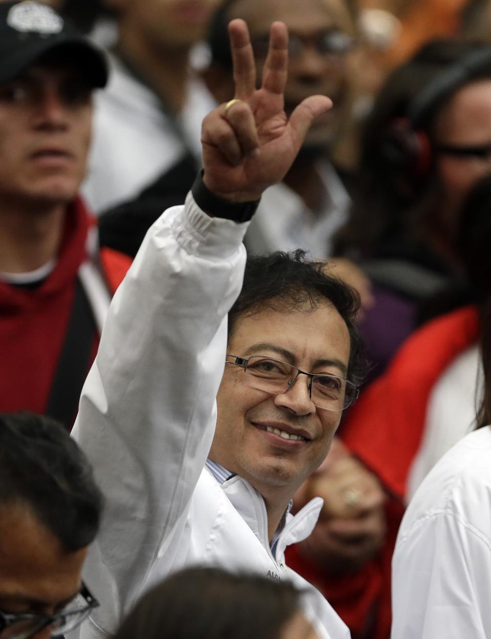 Bogota's mayor Gustavo Petro, center, waves to supporters as he arrives to city hall in Bogota, Colombia, Wednesday, April 23, 2014. Colombia's President Juan Manuel Santos reinstated Petro following a court order. Petro was removed from office in March after President Juan Manuel Santos refused to heed the Inter-American Human Rights Commission's call for a stay on the Inspector General's ouster of the mayor months earlier for alleged administrative missteps. (AP Photo/Fernando Vergara)