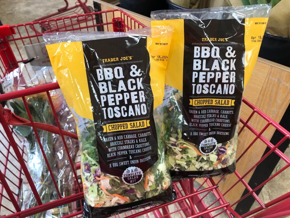 Two bags of Trader Joe's BBQ and black-pepper Toscano chopped salad in a red cart.