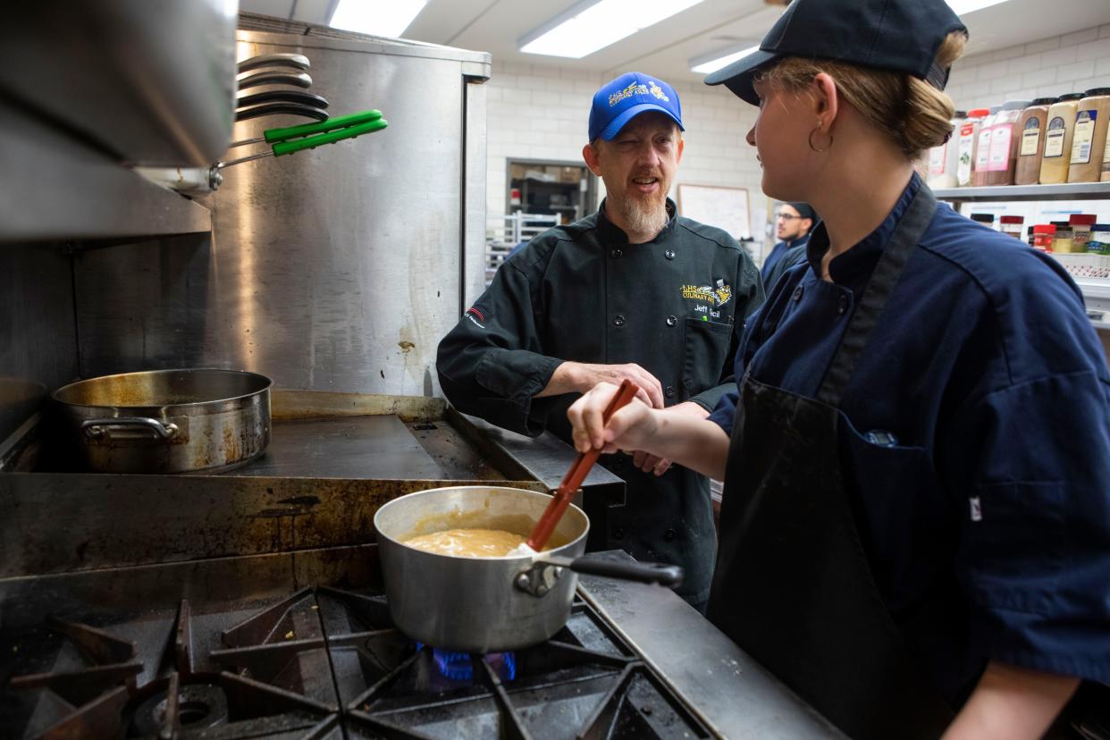 Lancaster High School Culinary Instructor Jeff Cecil (left) talks with junior Maggie Davis, 16, as she stirs up caramel she was making for a cheesecake in culinary class on Apr. 17, 2024, in Lancaster, Ohio.