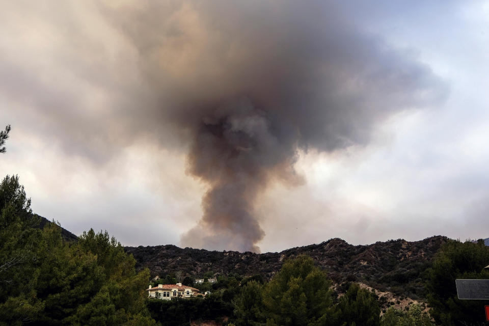 A plume of smoke rises from a wildfire behind a home in the Pacific Palisades area of Los Angeles, Sunday, May 16, 2021. (AP Photo/Ringo H.W. Chiu)