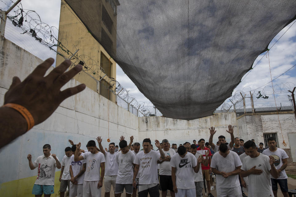 Prisoners pray before getting baptized inside an evangelical cellblock at the Penal Unit N11 penitentiary in Pinero, Santa Fe Province, Argentina, Saturday, Dec. 11, 2021. Prisoners who want to be allowed in an evangelical cellblock must comply with rules of conduct, including praying three times a day, giving up all addictions and fighting. (AP Photo/Rodrigo Abd)