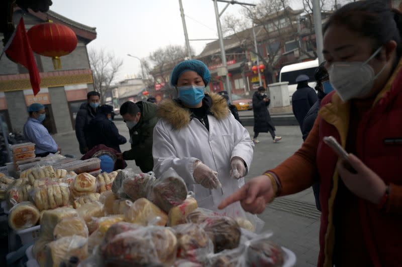 Woman wearing a face mask buys food from a stall set up by a restaurant outside its outlet near Drum Tower in Beiing