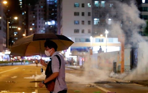 A man runs away from tear gas as riot police try to disperse anti-extradition bill protesters during a protest at Prince Edward in Hong Kong - Credit: Tyrone Siu/Reuters