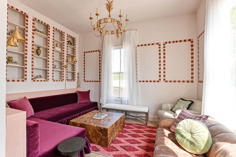 seating area with velvet bench sofa, gold candle chandelier, painted accents on walls and around built in shelves