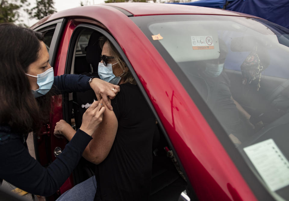 Una trabajadora de la salud inyecta a una mujer una dosis de la vacuna Sinovac para el COVID-19 en un sitio de vacunación en el estadio Nacional en Santiago, Chile, el martes 16 de marzo de 2021. (AP Foto/Esteban Félix)