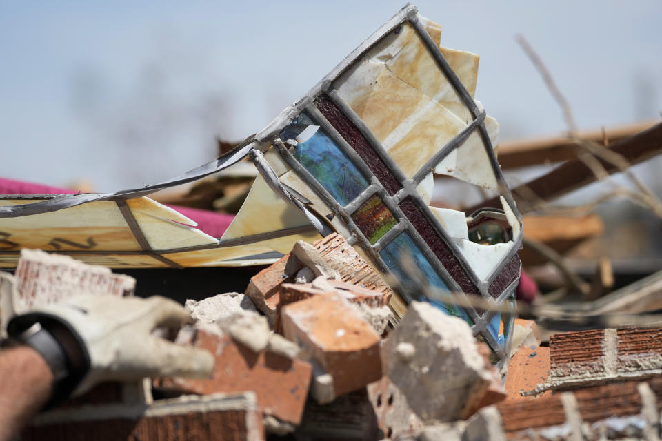 Charlie Weissinger reaches for a stained glass window frame while searching for his family's stained glass window in the rubble left from a March 24 tornado, that hit The Chapel of The Cross Episcopal Church in Rolling Fork, Miss., on March 29, 2023. The Weissinger family roots run deep in the 99-year old church and largely farming community and he expects his family will join members in rebuilding the church and repairing the family home which was damaged by the killer tornado. (AP Photo/Rogelio V. Solis)