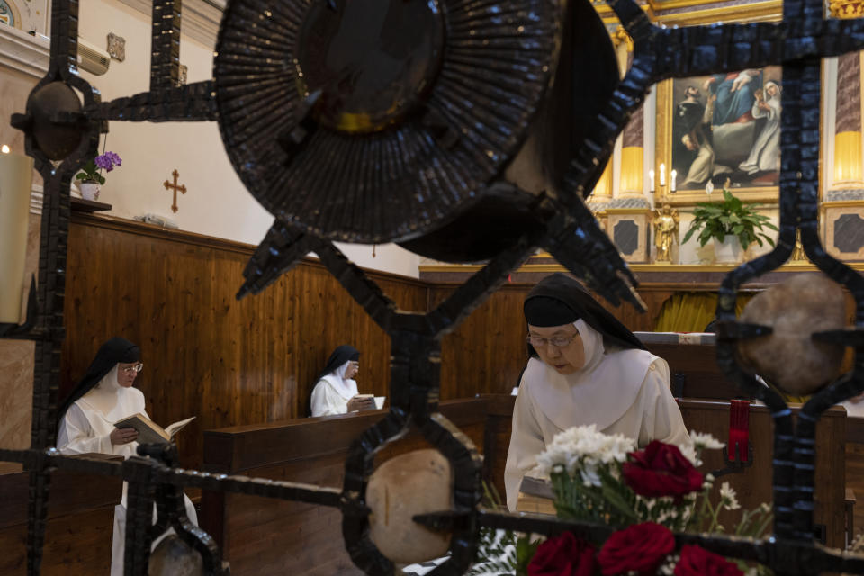 Sister María de Jesús bows her head as Sister María Flor de la Eucaristía, left front, and Sister Amparo de María pray during Mass in the Catholic Monastery of St. Catherine on the Greek island of Santorini on Tuesday, June 14, 2022. The nuns pray at least nine hours a day, most of it sung in Latin, Spanish and Greek. (AP Photo/Petros Giannakouris)