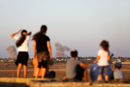 Israeli kids look over the Israeli Syrian border as smoke can be seen following an explosion at its Syrian side it is seen from the Israeli-occupied Golan Heights, Israel July 23, 2018. REUTERS/Ronen Zvulun