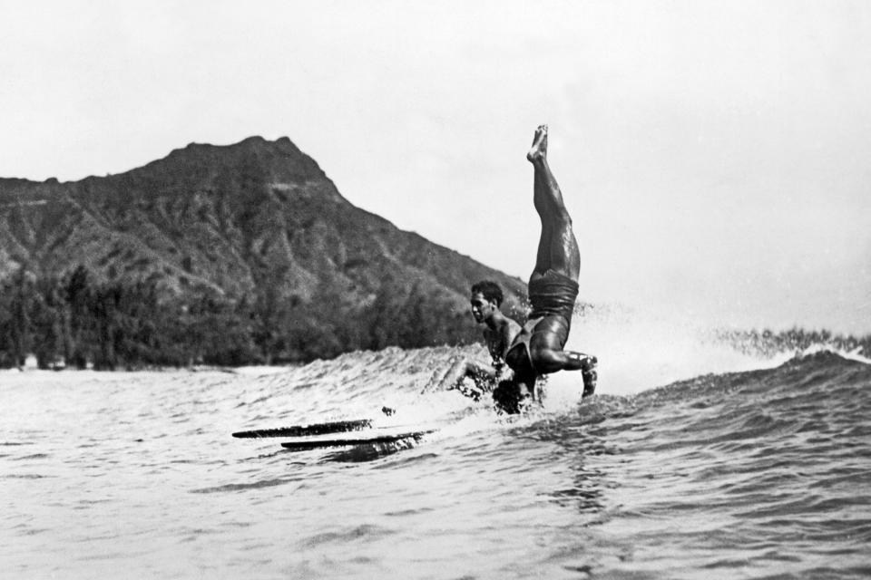 Image: A surfer at Waikiki Beach stands on his head as he rides a wave into the shore in Honolulu c. 1925. (Underwood Archives / Getty Images)