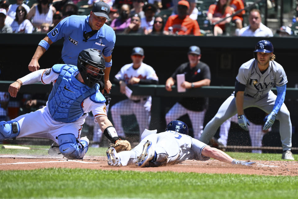 Tampa Bay Rays' Brett Phillips is tagged out by Baltimore Orioles designated hitter Adley Rutschman after attempting to score on double by Vidal Brujan during the second inning of a baseball game, Sunday, June 19, 2022, in Baltimore. (AP Photo/Terrance Williams)