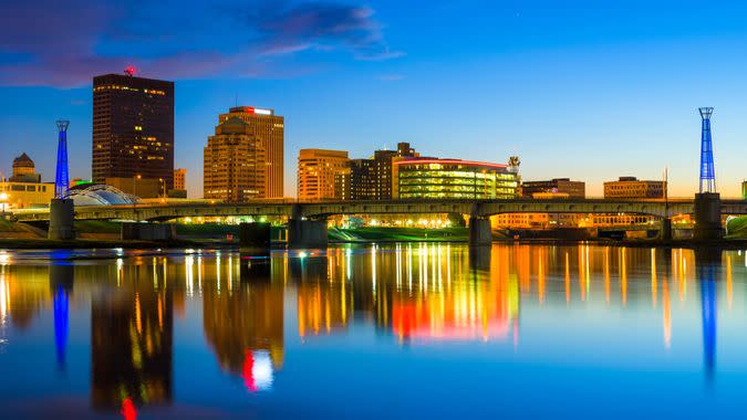 Downtown Dayton skyline with the Miami River and skyline reflections at dusk.