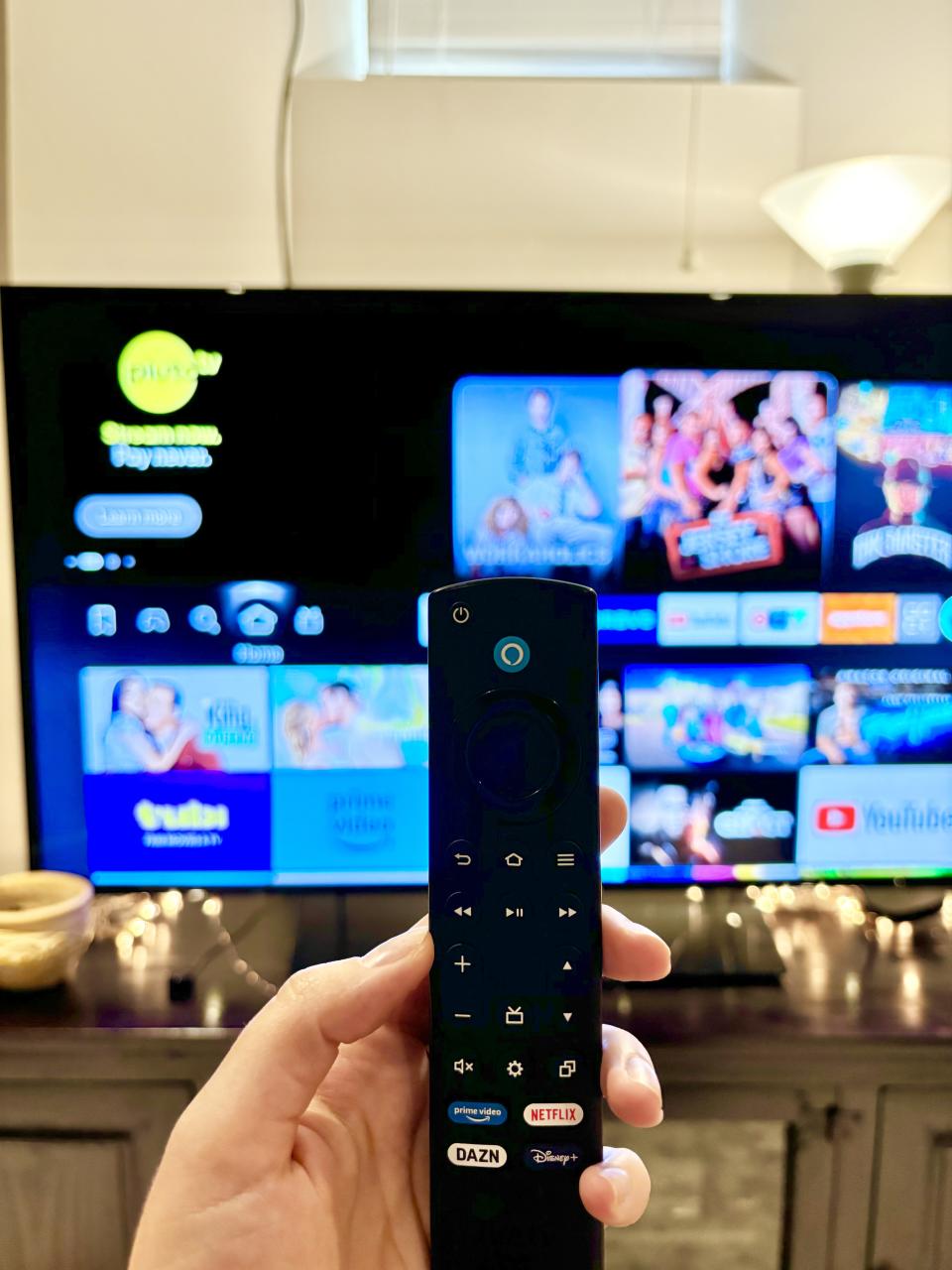 someone holding the Amazon Fire TV Stick against a tv in the background