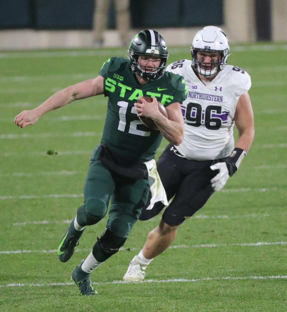 Michigan State quarterback Rocky Lombardi runs by Northwestern defensive end Trevor Kent for a first down during the second half of MSU's 29-20 win at Spartan Stadium at Saturday, Nov. 28, 2020.