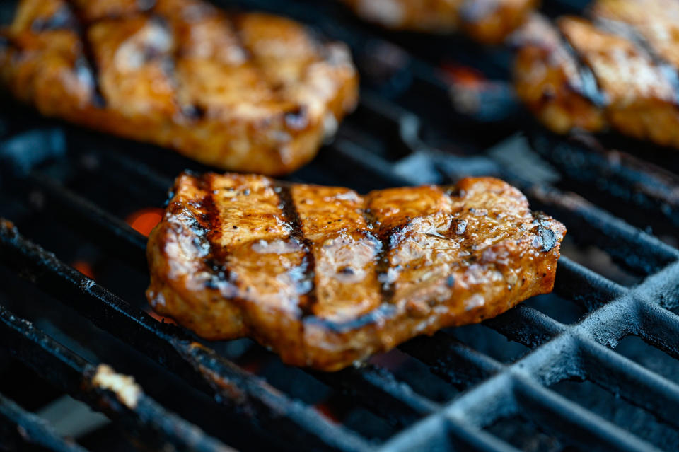 Grilled steaks with char marks cooking on a barbecue grill