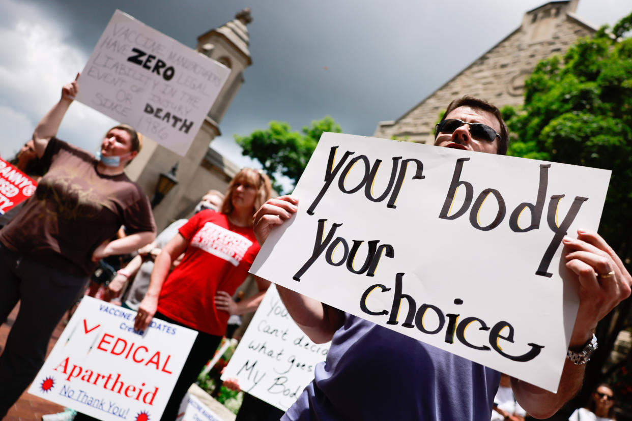 Protesters hold signs reading 