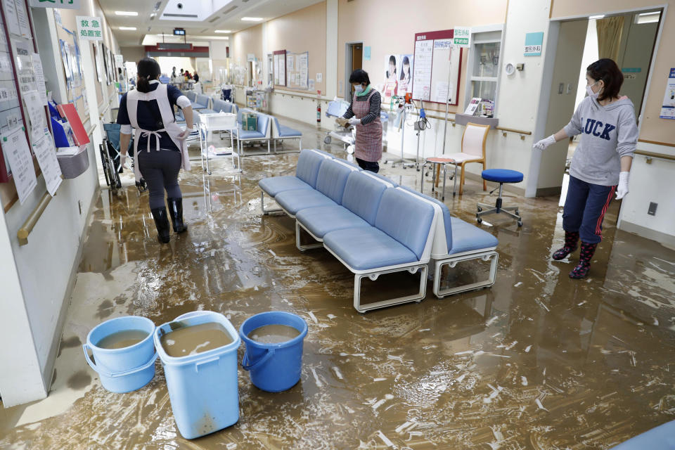 Staff members clean a hospital damaged by Typhoon Hagibis, in Marumori town, Miyagi prefecture, Japan Tuesday, Oct. 15, 2019. The typhoon hit Japan's main island Saturday, unleashing strong winds and dumping historic rainfall that caused more than 200 rivers in central and northern Japan to overflow, leaving thousands of homes flooded, damaged or without power. (Kyodo News via AP)