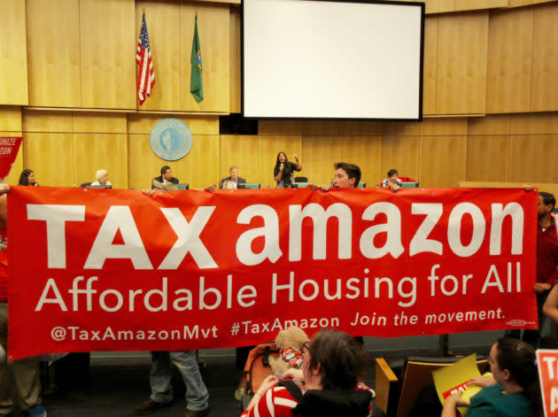 Supporters of the head tax rush the City Council chambers during a vote to repeal the controversial legislation in June. Behind the banner, Councilmember Kshama Sawant calls for order. (GeekWire Photo / Monica Nickelsburg) <strong><a href="https://www.geekwire.com/2018/seattle-repeals-head-tax-7-2-dramatic-reversal-leaves-city-divided-homeless-crisis/" rel="nofollow noopener" target="_blank" data-ylk="slk:Read the story.;elm:context_link;itc:0;sec:content-canvas" class="link ">Read the story.</a></strong>