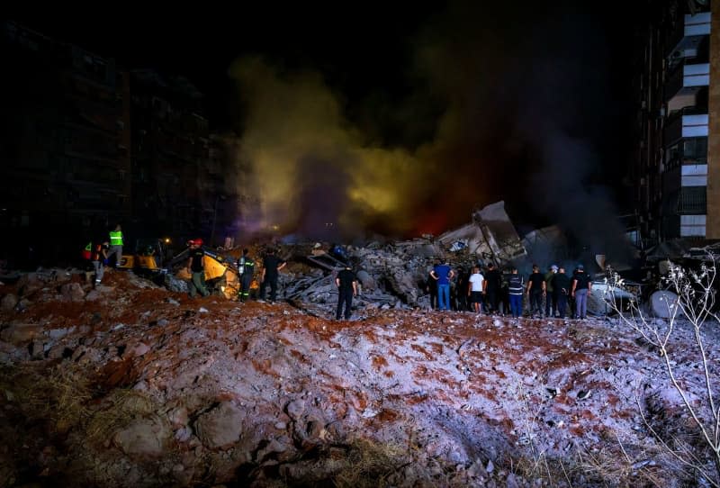 Rescue workers gather at the site of a massive Israeli airstrike on Hezbollah's pro-Iranian headquarters in Beirut's southern suburbs. Marwan Naaman/dpa