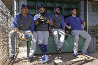 Texas Rangers players from left, Ronald Guzman, Rougned Odor, Elvis Andrus and Todd Frazier wait in the dugout to start batting practice during spring training baseball workouts Monday, Feb. 17, 2020, in Surprise, Ariz. (AP Photo/Charlie Riedel)