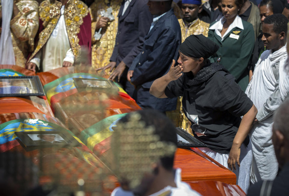 A relative blows a kiss towards empty caskets draped with the national flag at a mass funeral at the Holy Trinity Cathedral in Addis Ababa, Ethiopia Sunday, March 17, 2019. Thousands of Ethiopians have turned out to a mass funeral ceremony in the capital one week after the Ethiopian Airlines plane crash. Officials have begun delivering bags of earth to family members of the 157 victims of the crash instead of the remains of their loved ones because the identification process is going to take such a long time. (AP Photo/Mulugeta Ayene)